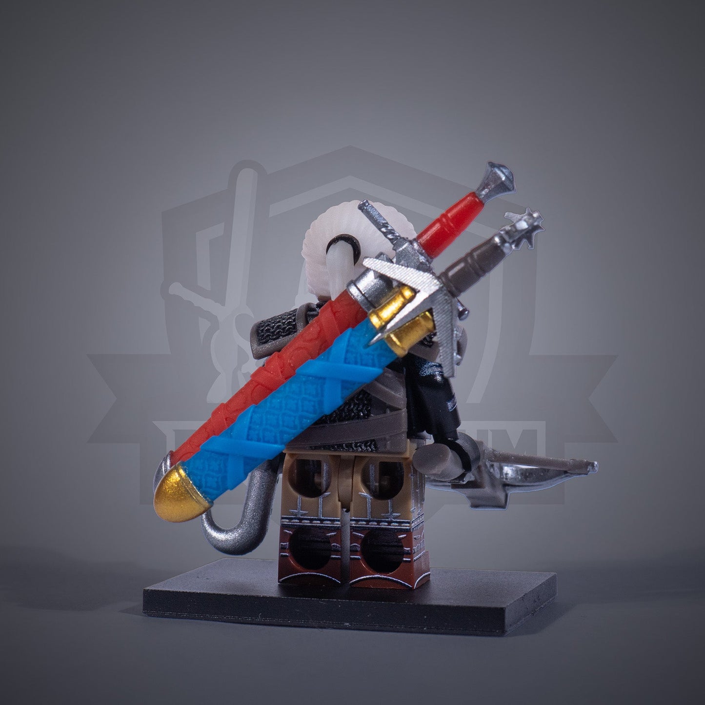 Toy figure of a Witcher with armor and two swords on a gray background