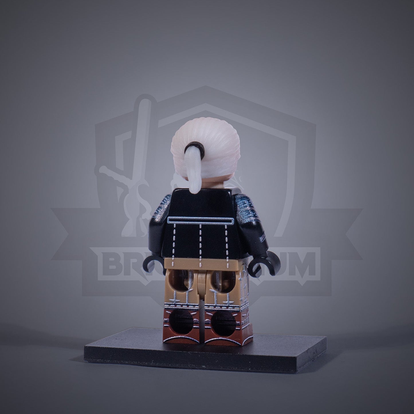 Toy figure of a Witcher without armor on a gray background